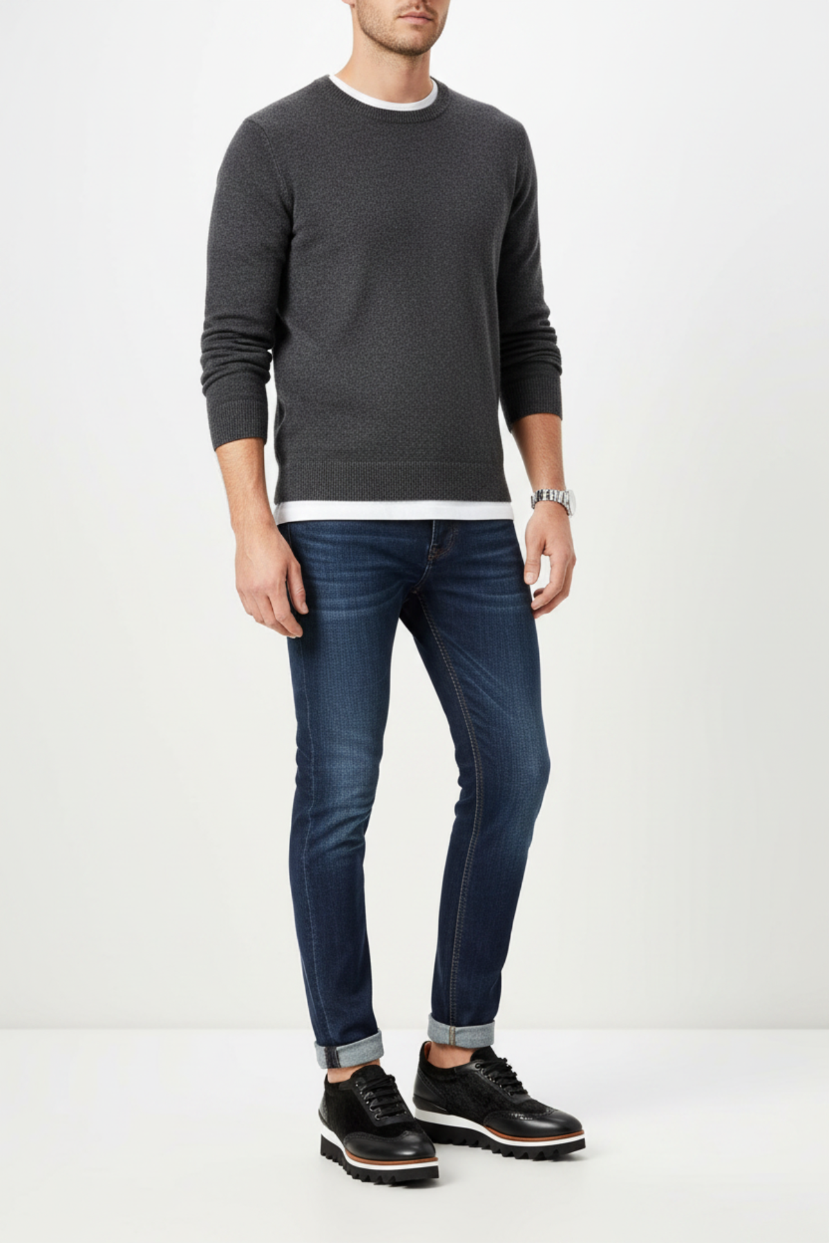Male model wearing men's black leather and pony hair brogue Oxford with chunky white lug sole, styled with dark slim jeans and grey crew-neck sweater