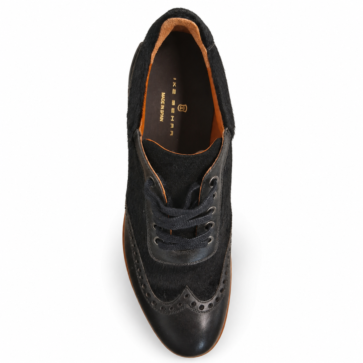 A single black suede and leather wingtip oxford shoe shown from a top-down view on a white background. The shoe features dark laces, decorative brogue perforations, and a warm brown interior lining with 'JASPER MADE IN SPAIN  printed in gold.