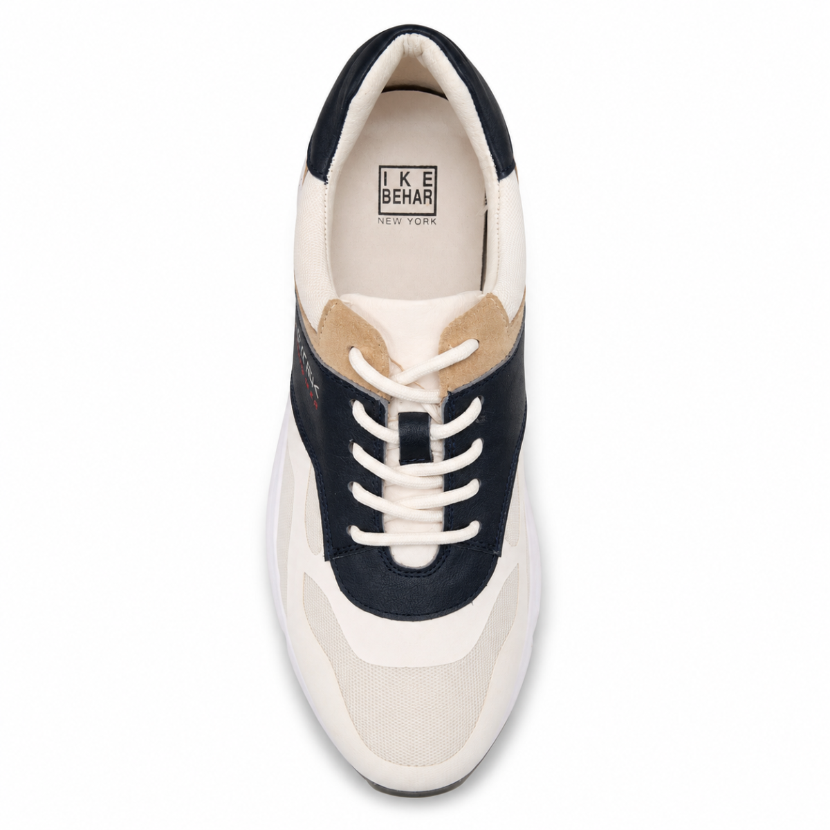 A top-down view of a low-top sneaker by IKE BEHAR, featuring a cream and navy blue color-blocked design with beige suede overlays and white laces, set against a plain white background.