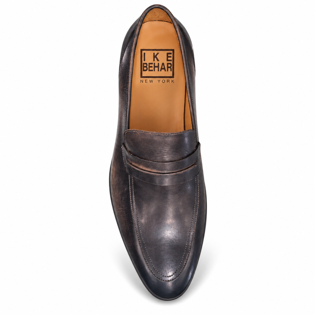 A single dark brown leather penny loafer shown from a top-down view on a white background. The shoe features a distressed finish and a tan interior with the brand name 'IKE BEHAR NEW YORK' printed on the insole.