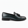 A single men's loafer in a textured, iridescent metallic finish that shifts between silver, blue, and green, featuring a black tassel detail on the strap and a black sole.