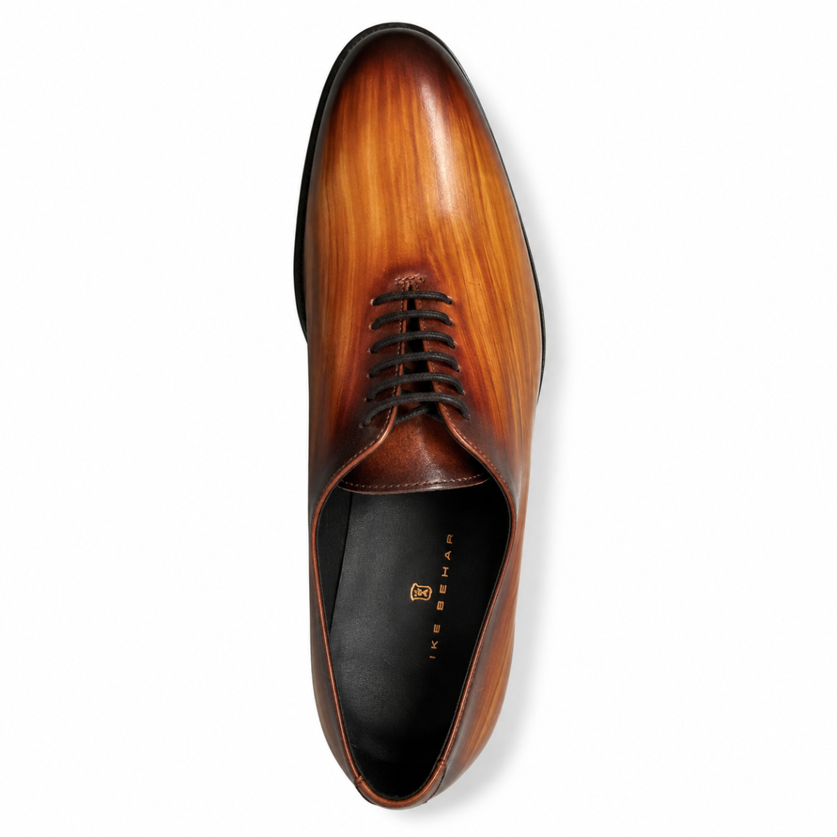 A single men's oxford dress shoe shown from a top-down view on a white background. The shoe features a glossy, warm cognac-brown wood-grain finish on the toe and quarter panels, with a darker brown vamp and black laces.