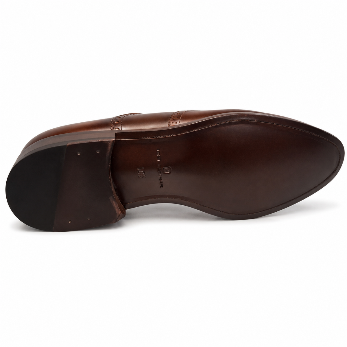 A close-up, top-down view of a brown leather dress shoe's outsole, showing the V-shaped center strip and embossed branding on a white background.