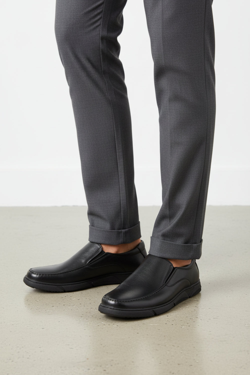 A black slip-on leather shoe with a tan interior lining and a black sole, shown from a three-quarters angle on a white background.