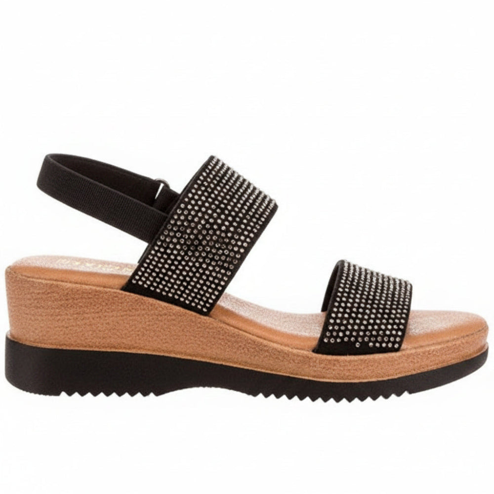 A women's wedge sandal with black straps embellished with silver rhinestones, featuring a tan cork-textured midsole and a black outsole, shown from a side profile on a white background.