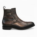A dark brown distressed leather ankle boot with double buckle strap details and a pull loop, shown from a side profile on a white background.