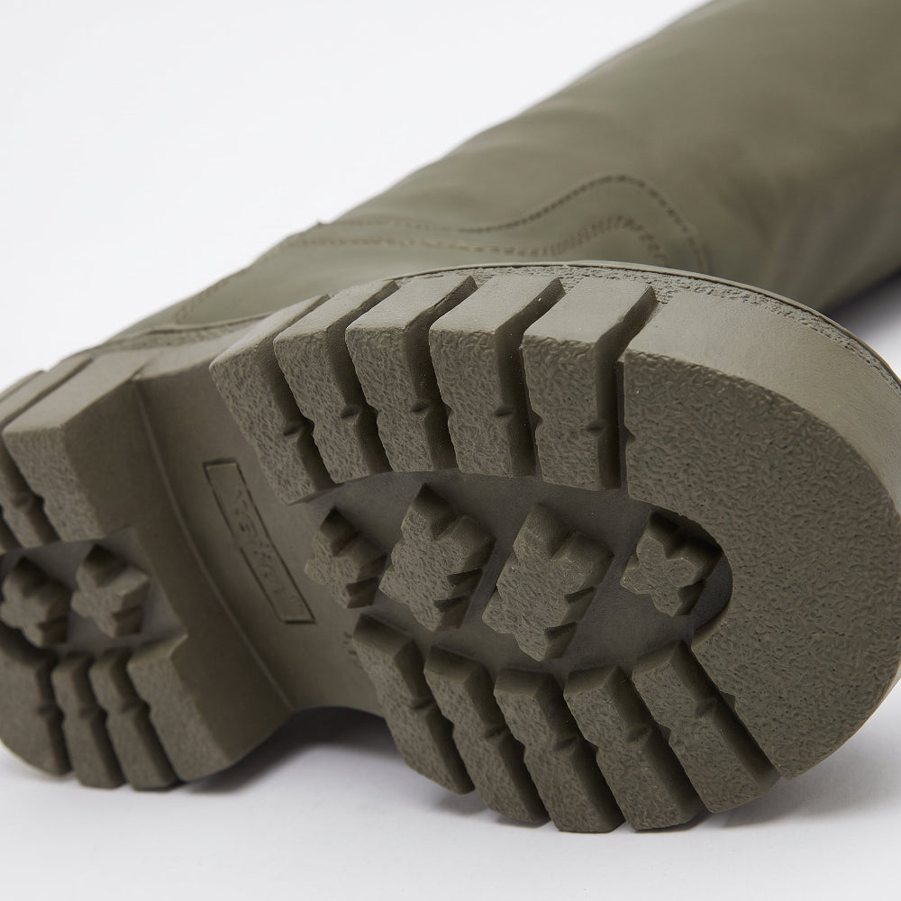 Close-up of the treaded outsole of an olive green boot on a white background.