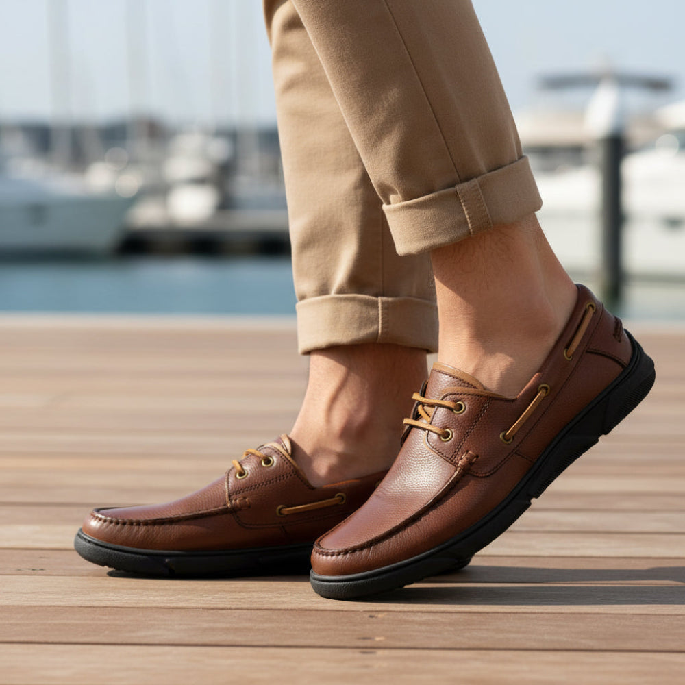 A brown leather boat shoe with tan laces and brass-tone eyelets, shown in a side profile on a white background.