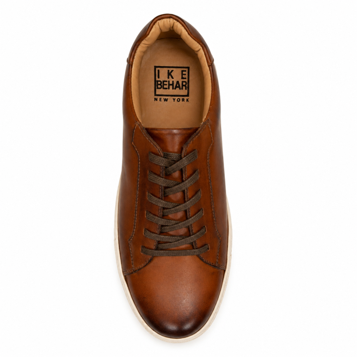 A top-down view of a brown leather sneaker by Ike Behar, featuring dark brown laces and a light beige outsole, set against a plain white background.